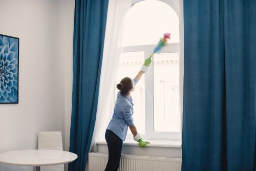 lady cleaning the curtains and window glass