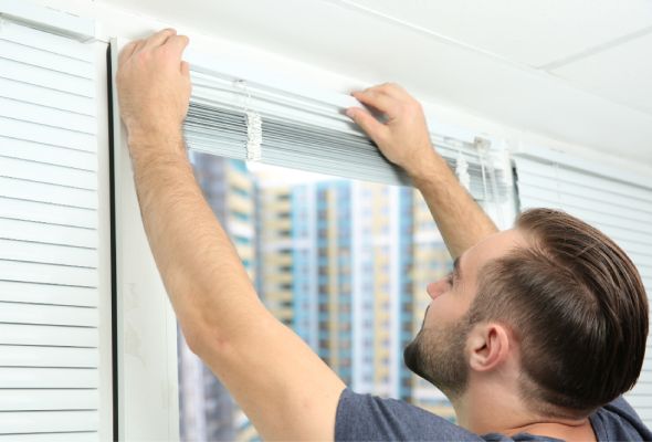 a man is showing how to repair & How to lower blinds with 4 strings