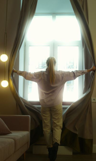 Girl opening the custom-made drapes in her bedroom