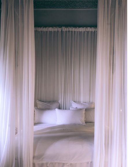 White sheer curtains are paired in a bed room around the bed.